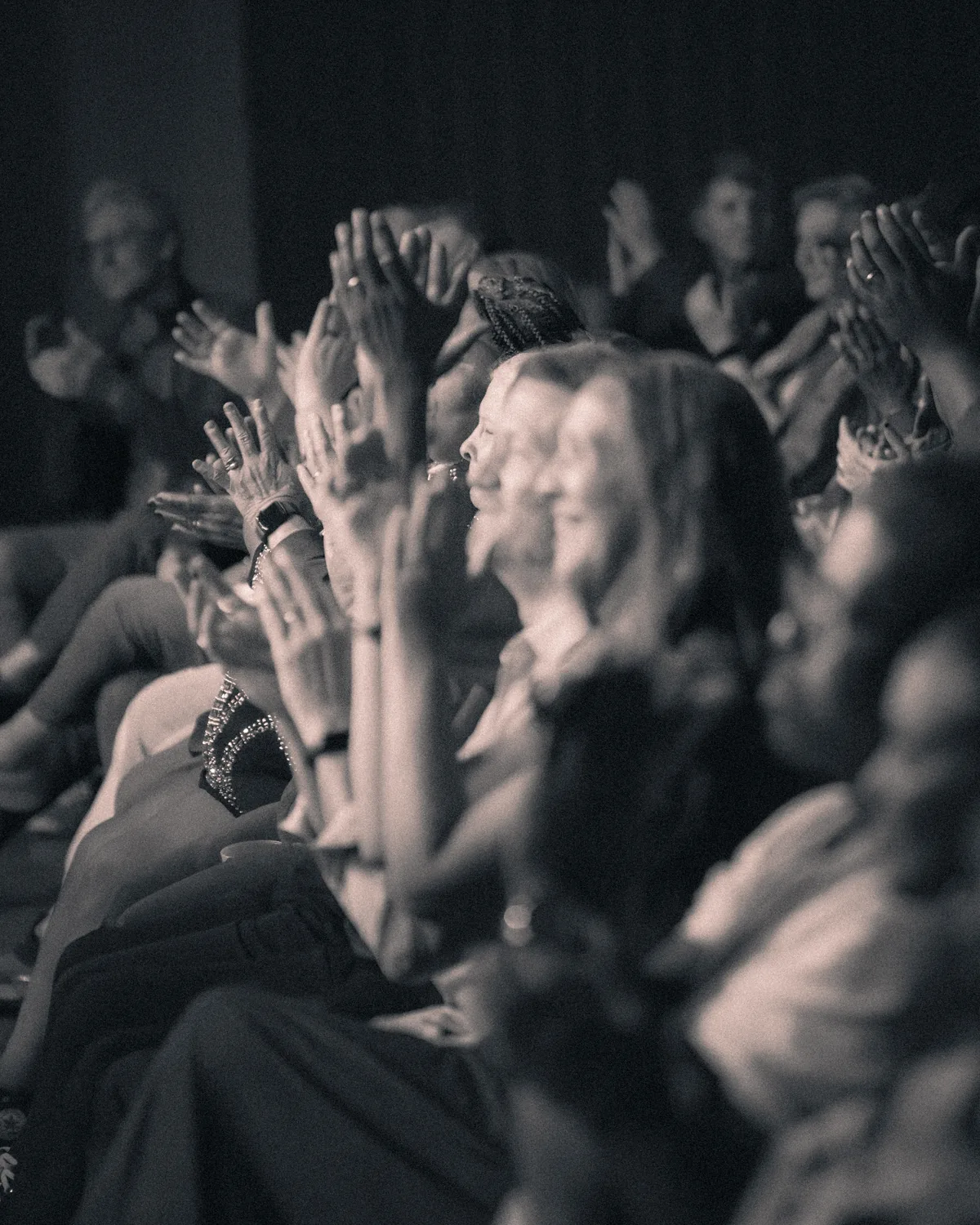 Concert audience members raising hands and applauding during live music performance in St. Augustine, Florida
