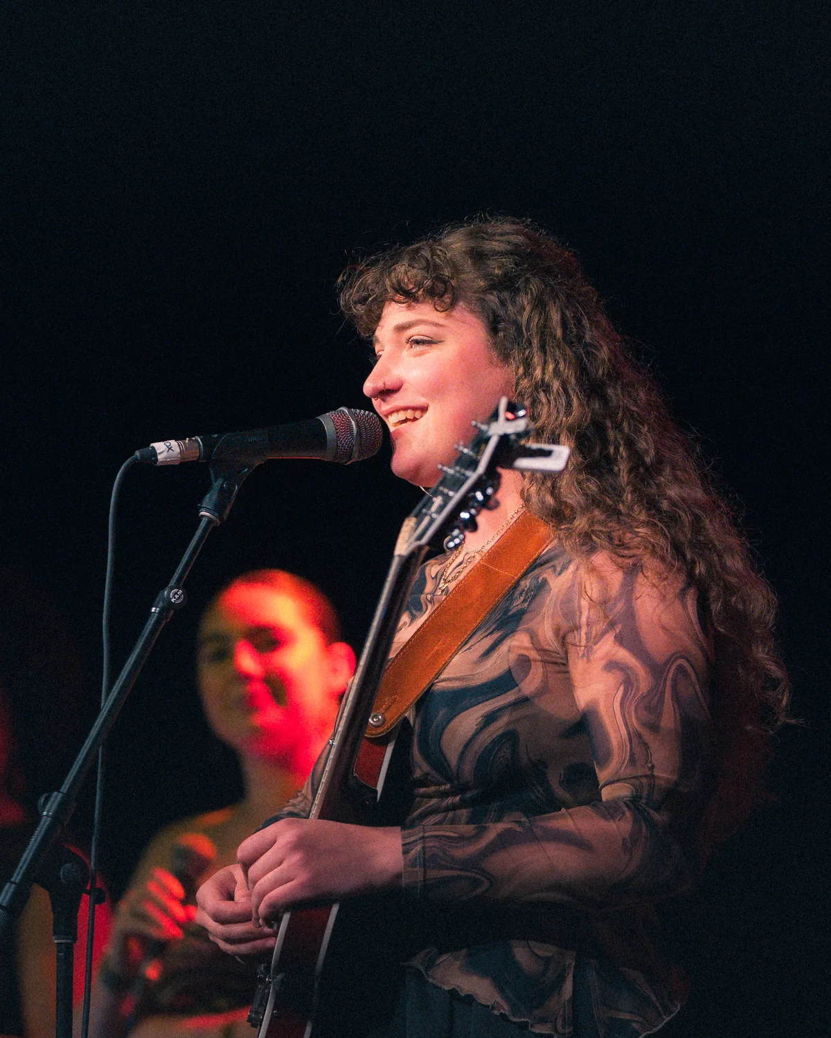 Hannah Stokes performing with guitar and microphone at Fort Mose Jazz Festival in St. Augustine, Florida